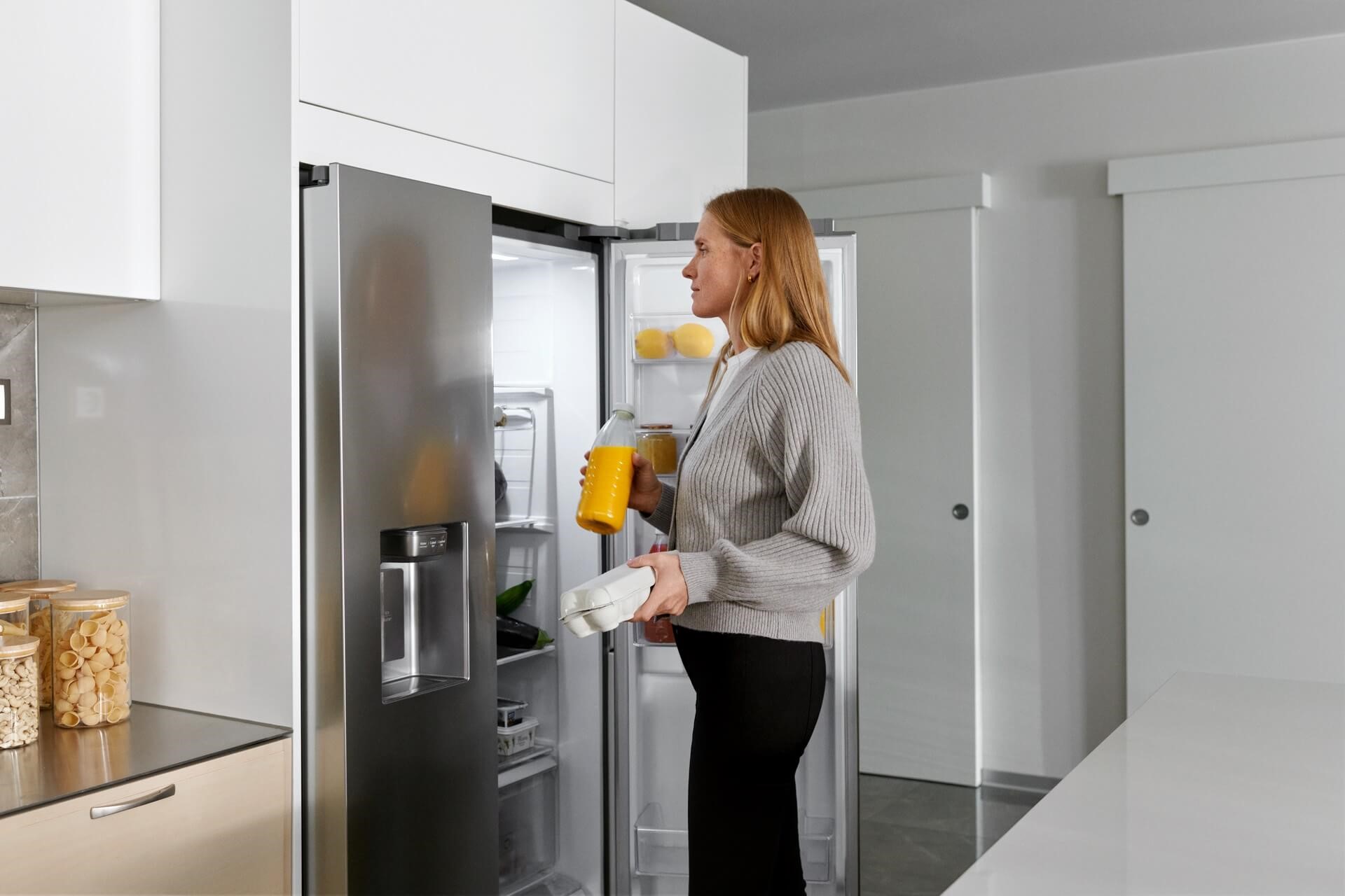 Een vrouw pakt eieren en sinaasappelsap uit een grote koelkast  | energieverbruik berekenen