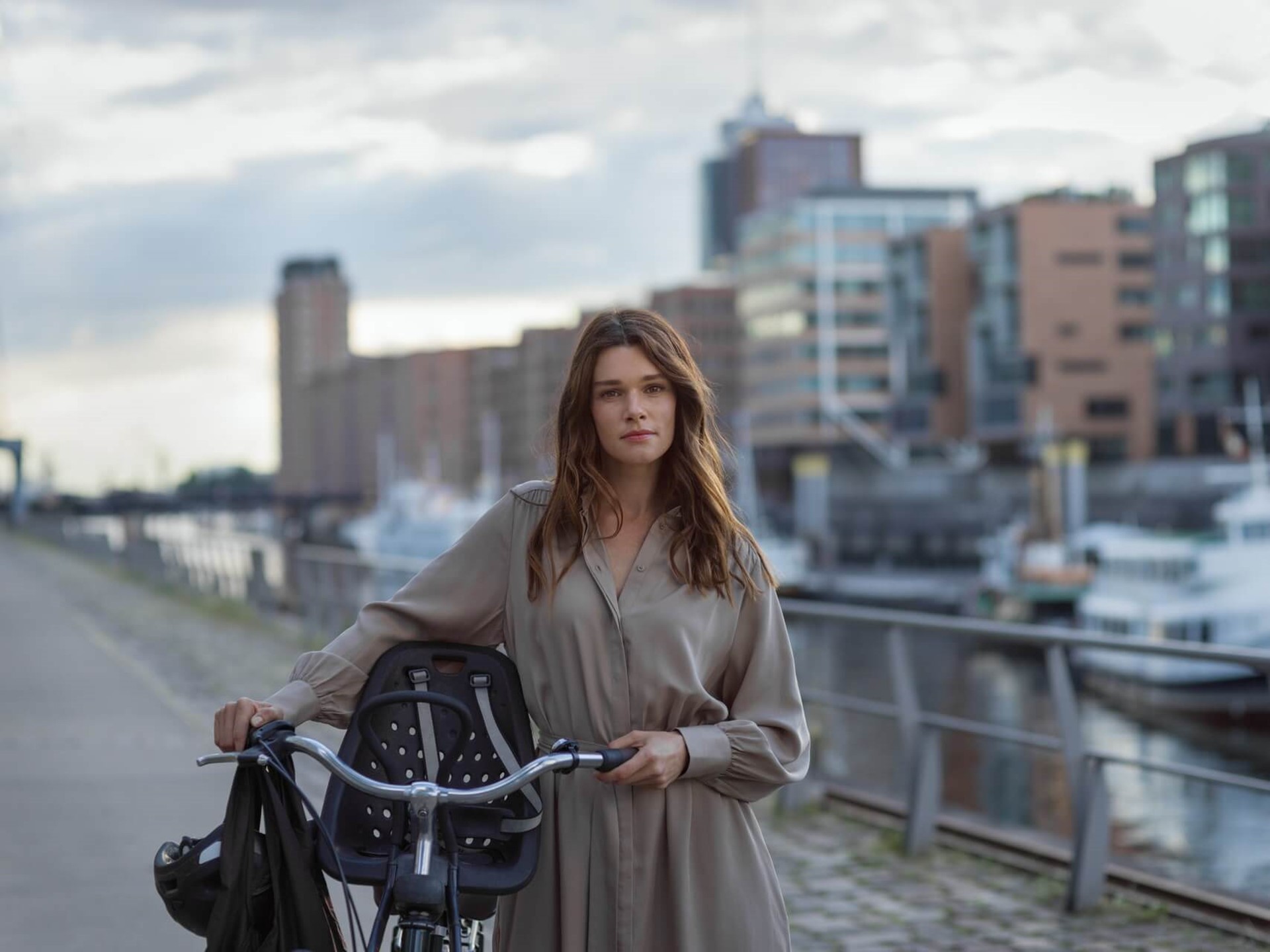 Een vrouw staat met de fiets aan de hand in een haven met nieuwbouwappartementen | Vattenfall over overstappen energieleverancier