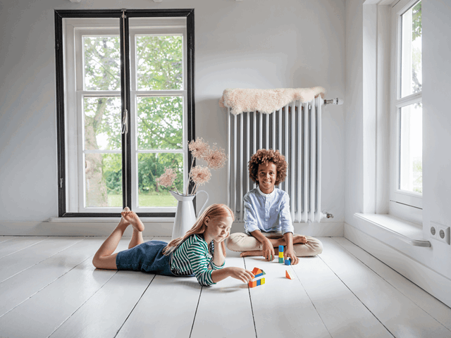 Kinderen spelen op vloer in met stadswarmte verwarmde woonkamer